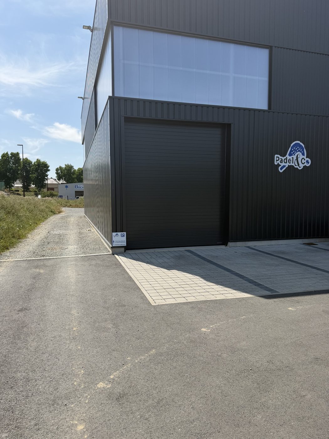 La façade noire du complexe avec le logo Padel and Co