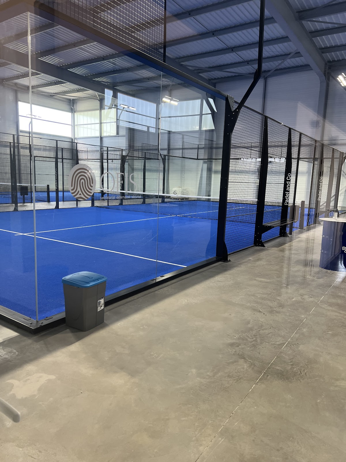 Les pistes bleues vues à travers les parois vitrées siglées Padel and Co